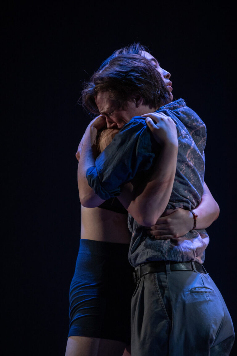 Photo taken by William Innes of actors June Sung and Quinn Andres embracing on stage during a performance of the play Immolation at the University of Waterloo's Theatre of the Arts.