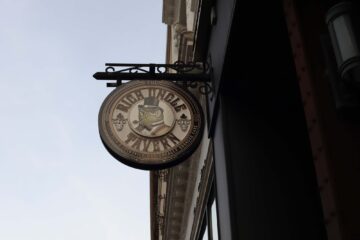 Photograph of the outdoor shop sign for The Rich Uncle Tavern (now closed), depicting a dapper owl in a top hat smoking a pipe.