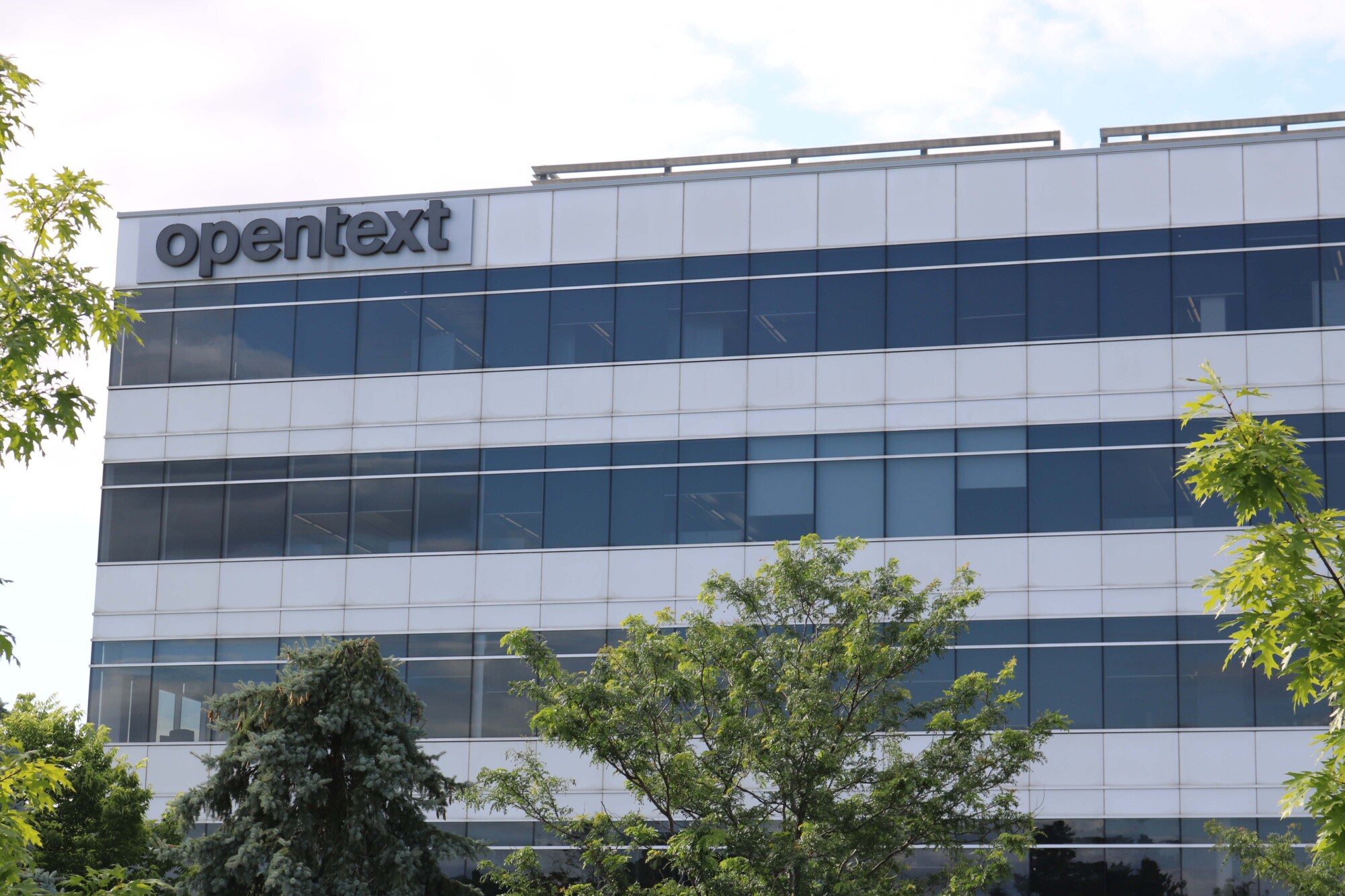 Photo of the OpenText head office from the outside. A sign reading "OPENTEXT" is mounted at the top left corner of the building.