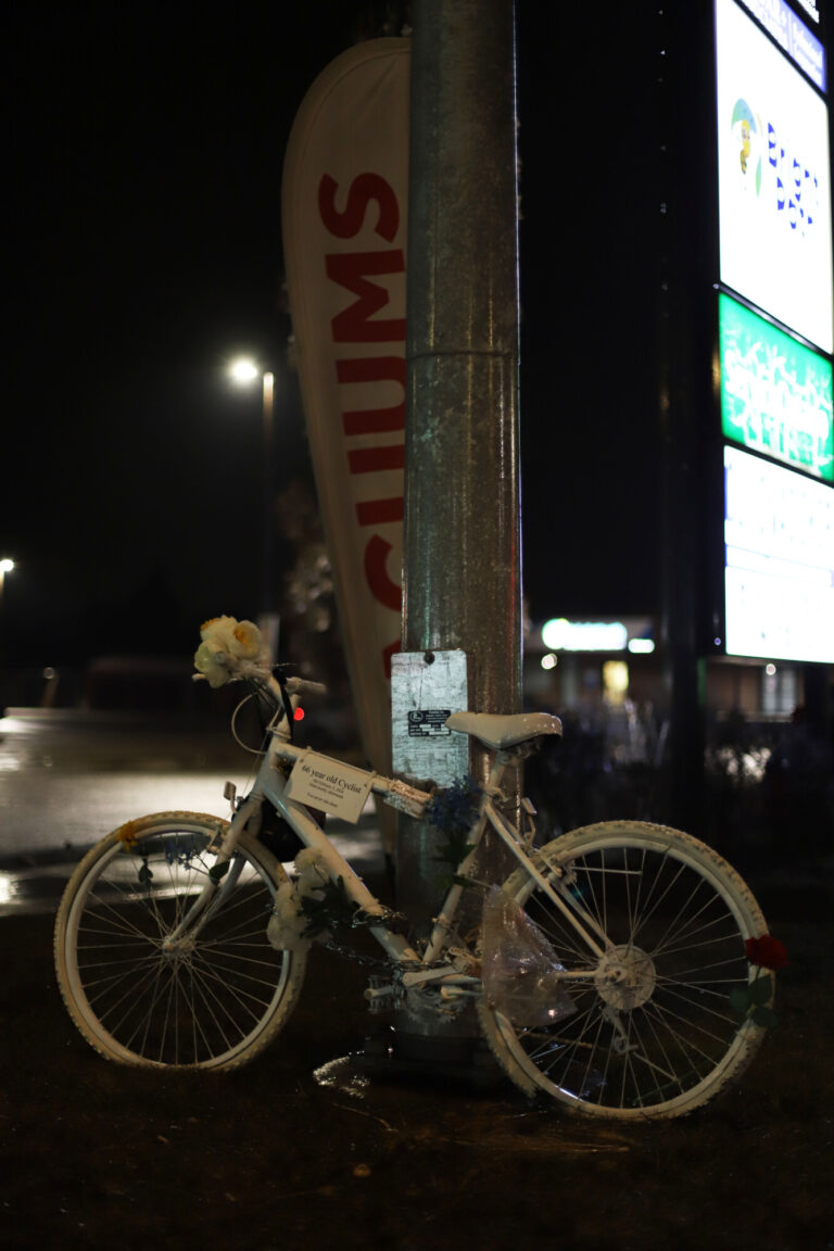 A bike that is painted all white is chained to a pole.