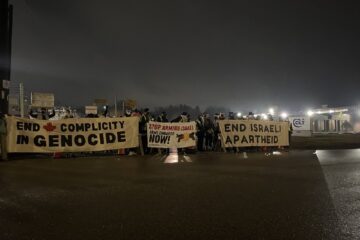 Photo of protesters are holding up banners reading "END COMPLICITY IN GENOCIDE" and "END ISRAELI APARTHEID" and blockade the entrance to the Colt Canada building in Kitchener, Ontario.