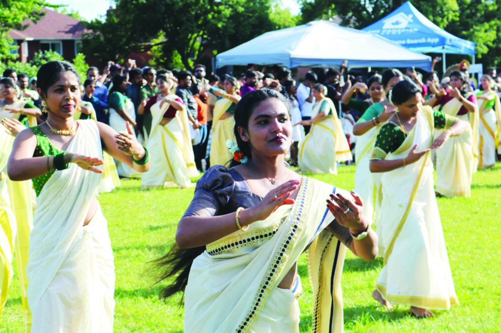 Photo of a group of women dancing in unison outside at the KW Onam Carnival.