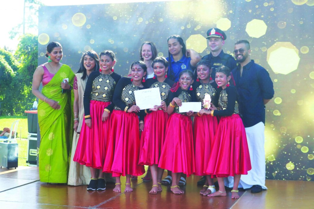 Photo of people on stage, including Liberal Party of Canada MP Bardish Chagger, Green Party MPP Aislinn Clancy and a team of young dancers, posing for a photo at the KW Onam Carnival.