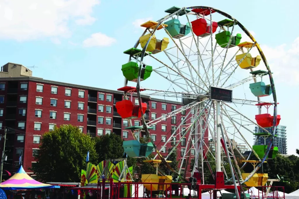 Photo of a colourful ferris wheel, taken on a sunny day during Waterloo Region's Busker's Carnival, also called Busker Fest.