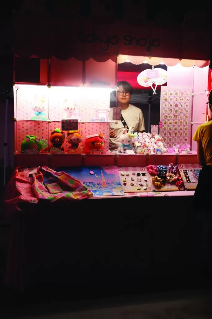 Photo of a vendor table at the Kitchener Far East Asian Night Market. The display is almost entirely pink and features numerous stuffed animals, stickers, scrunchies and fans.