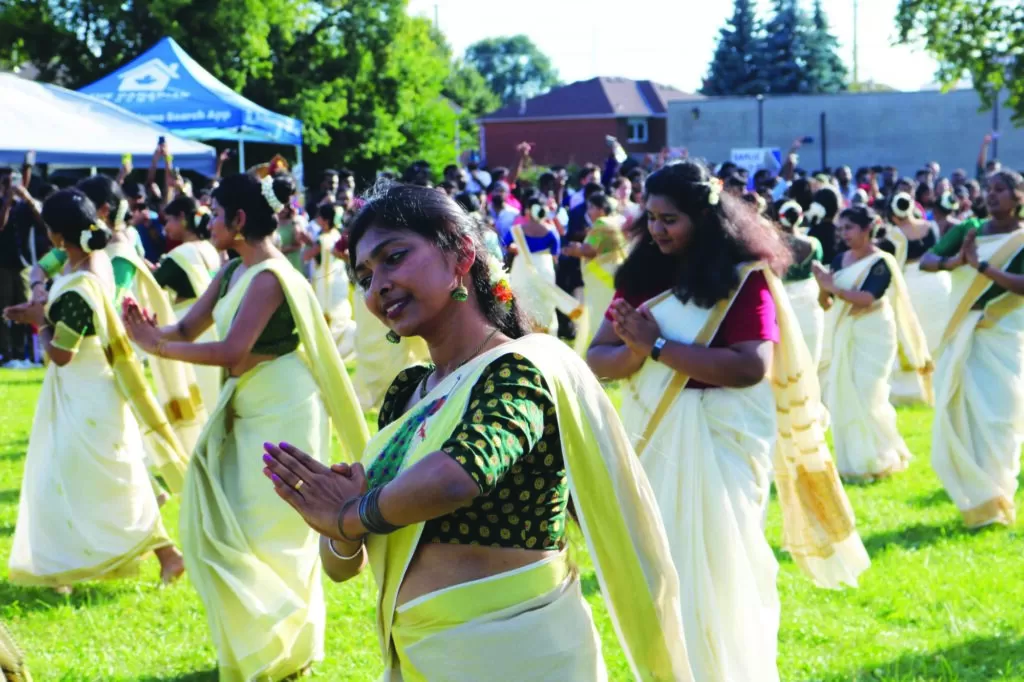 Photo of a group of women dancing in unison outside at the KW Onam Carnival.